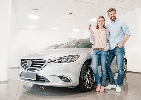 A Couple Standing and Smiling in Front of New Car with Car Insurance in Concord, North Carolina