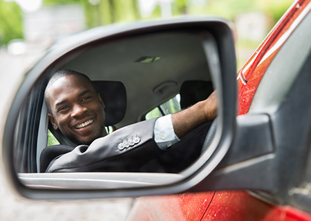 Man Smiling in Side View Mirror of Car with Car Insurance in Concord, North Carolina