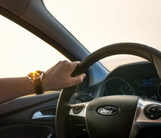 A hand on the steering of a car with Car Insurance in Gastonia 